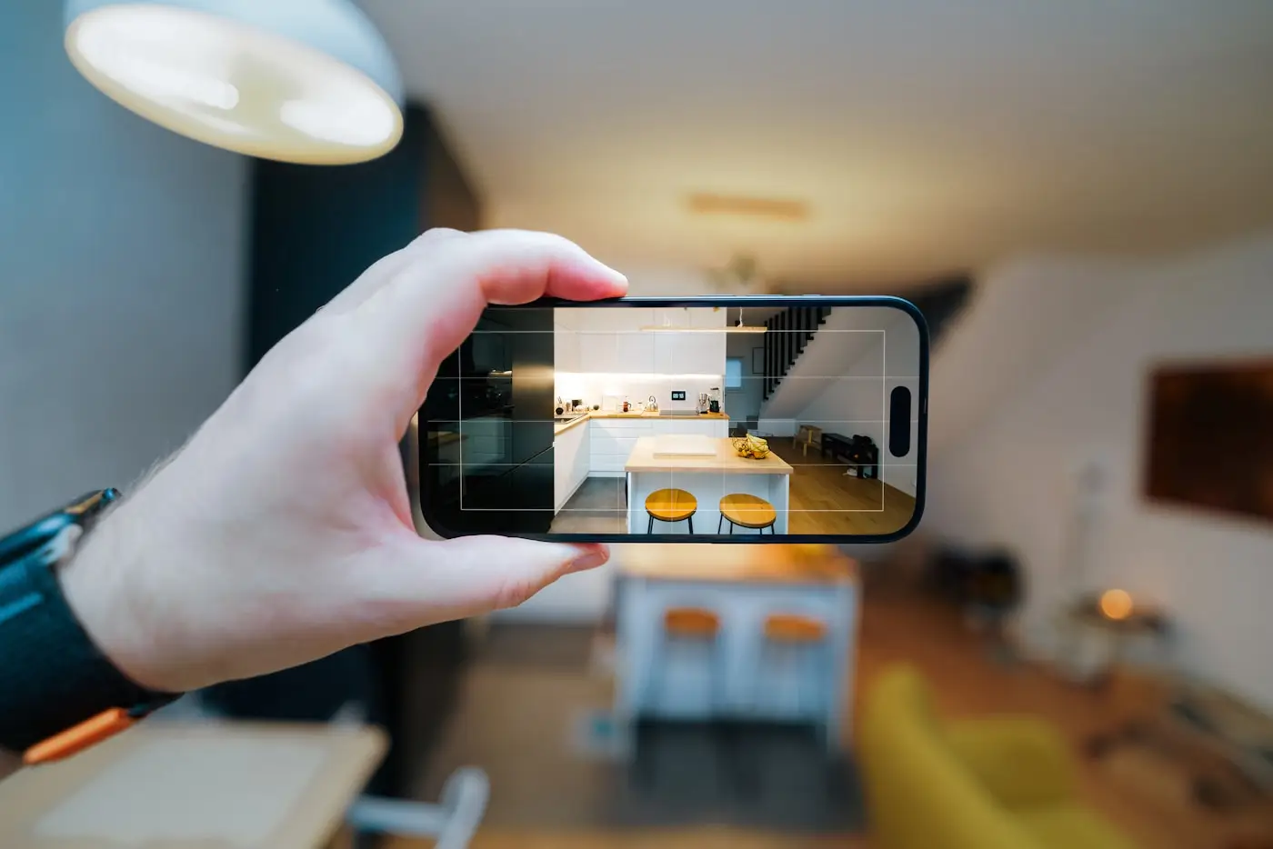 Hand hält Smartphone und fotografiert ein Wohnzimmer