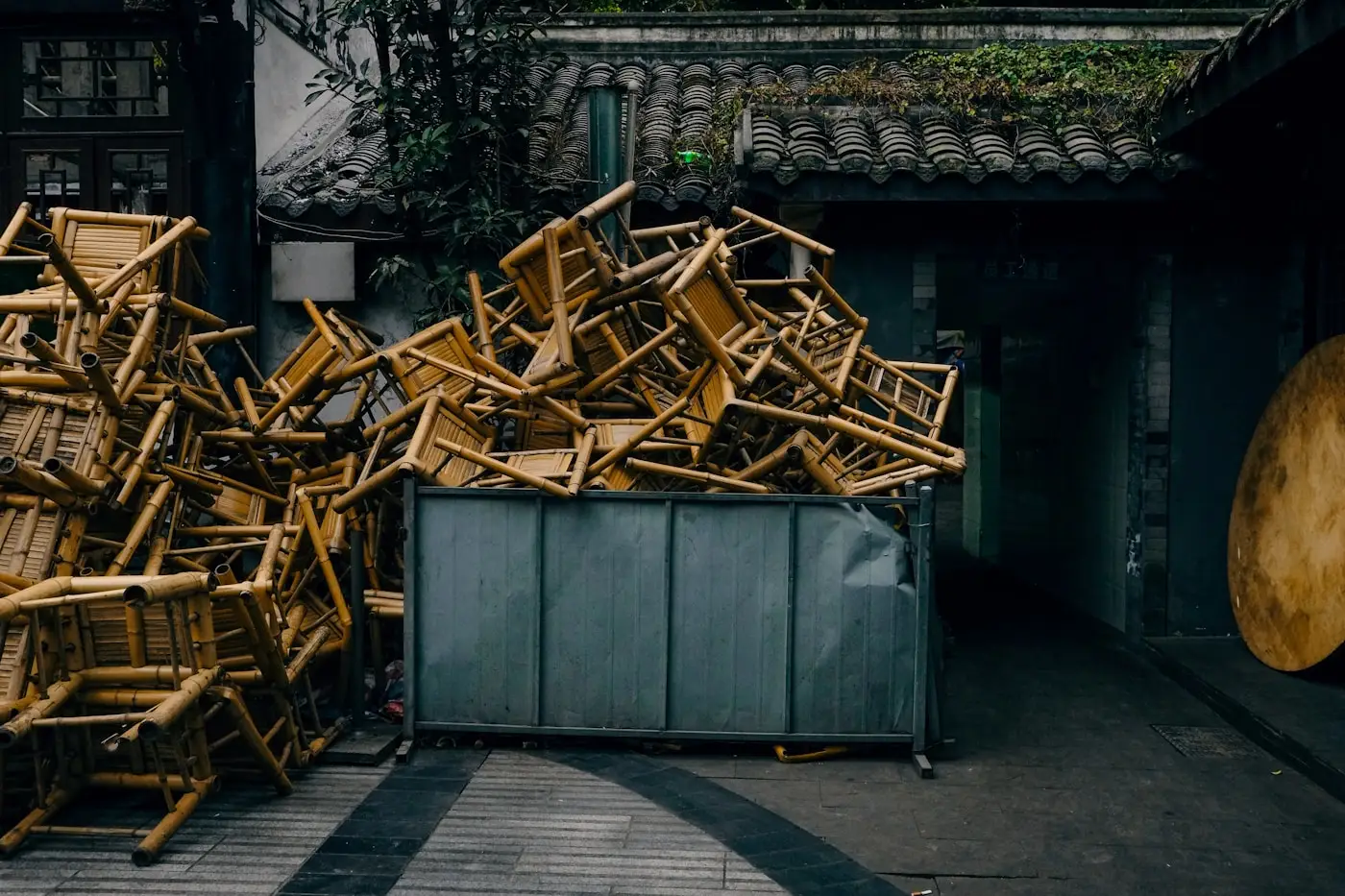 Alte Holzstühle gestapelt in einem Metallcontainer
