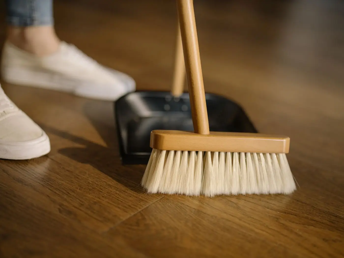 Handfeger und Kehrschaufel auf einem gefegten Holzboden