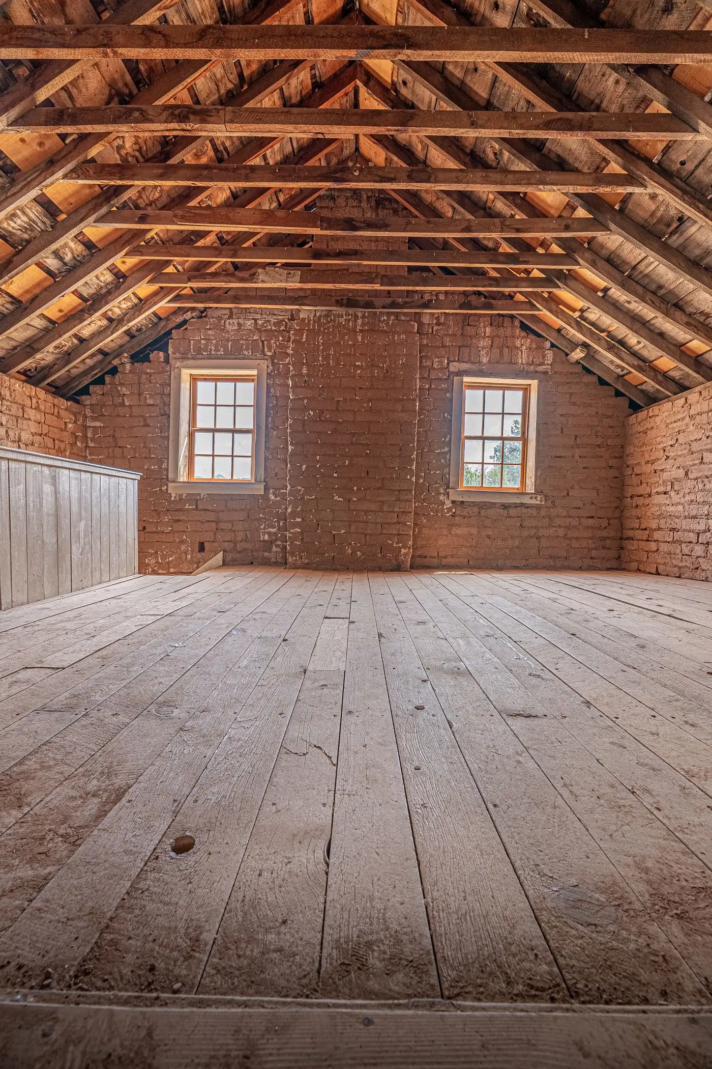 Leerer Dachboden mit freiliegenden Holzbalken und Backsteinwänden