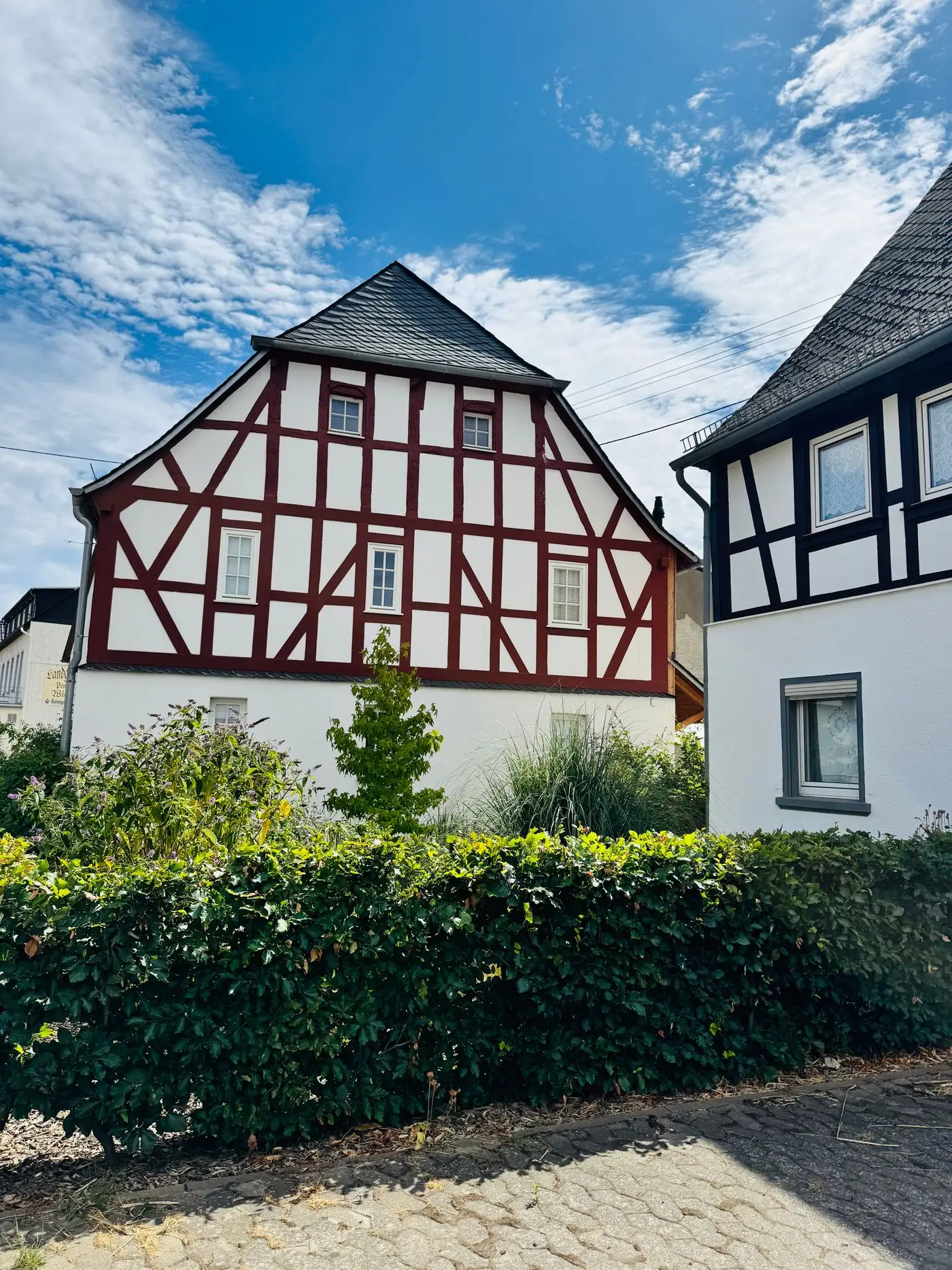 Fachwerkhaus mit Hecke unter blauem Himmel